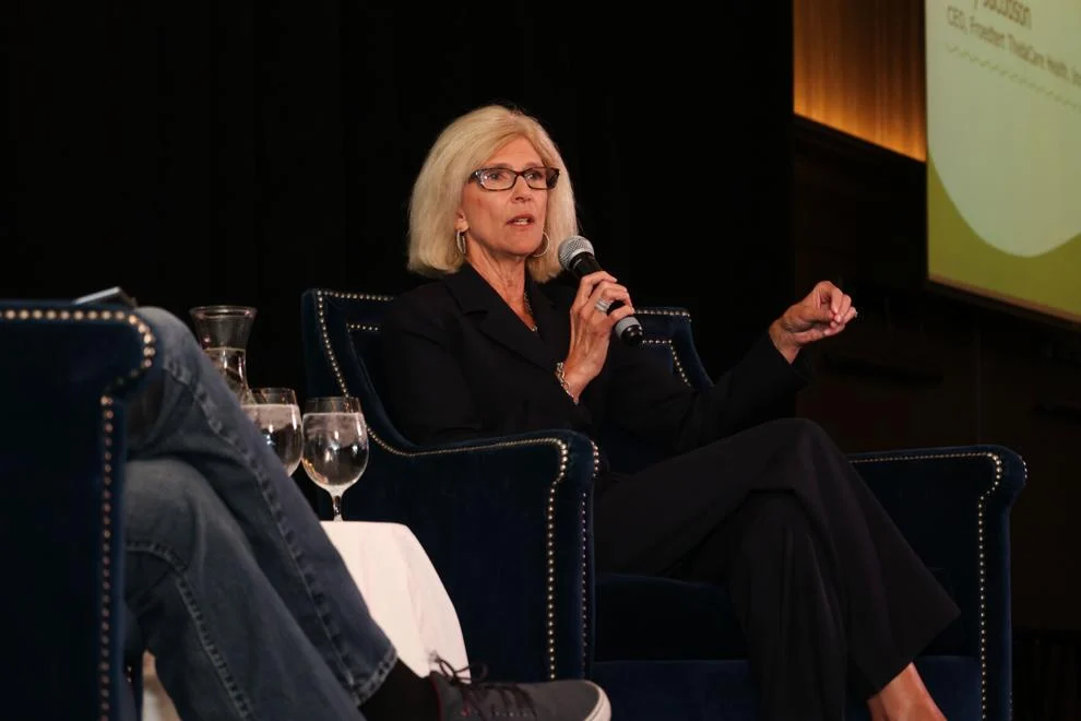 Woman speaking at conference holding a microphone.